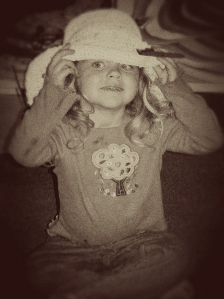 E tries on a hat while shopping
